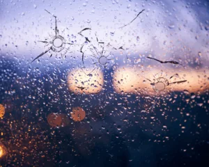 Bullet holes in glass against the background of a blurred city close up. Mass shooting concept