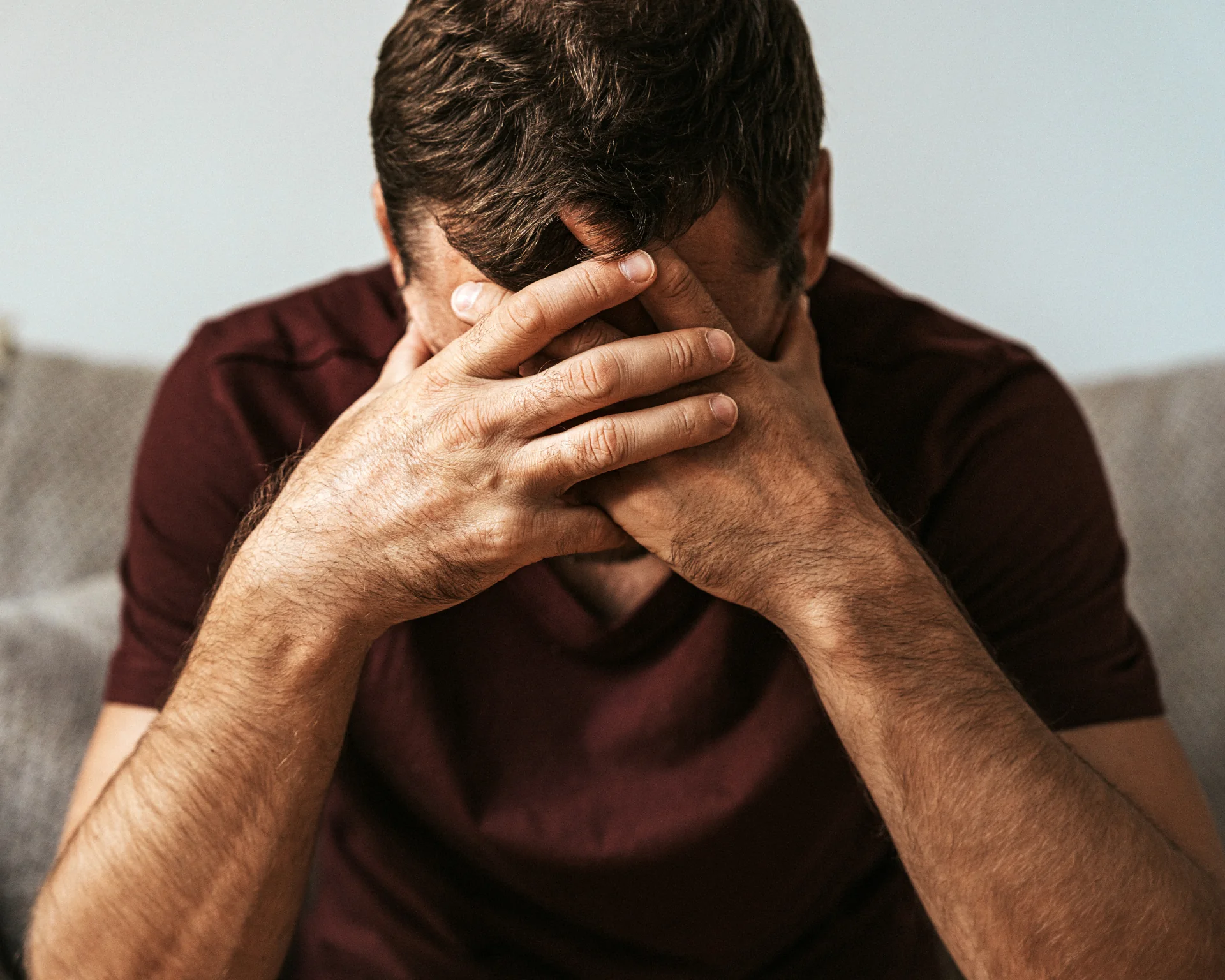 Stressed man hiding face behind hands in frustration and despair