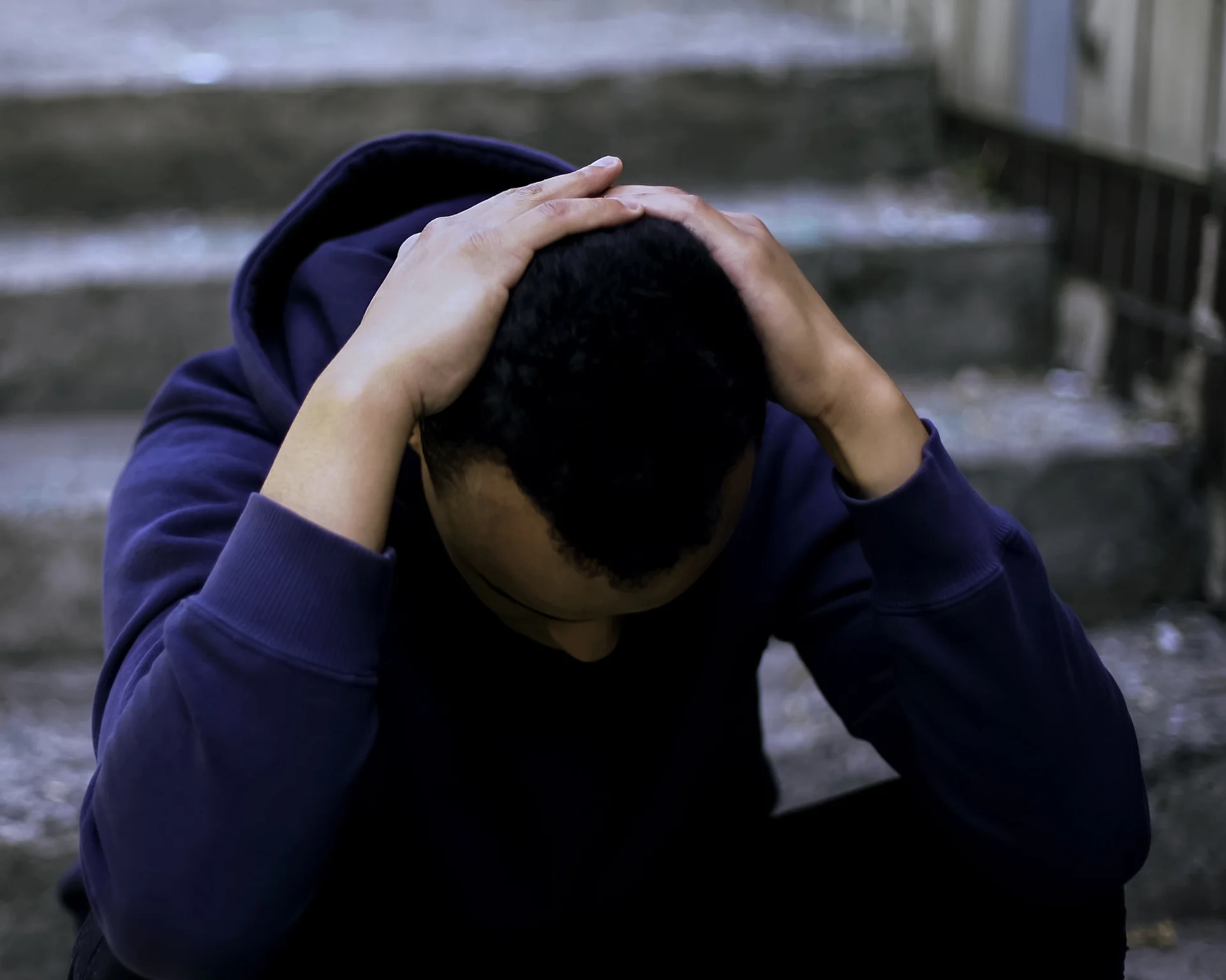 young man sitting on the stairs with his head in his hands