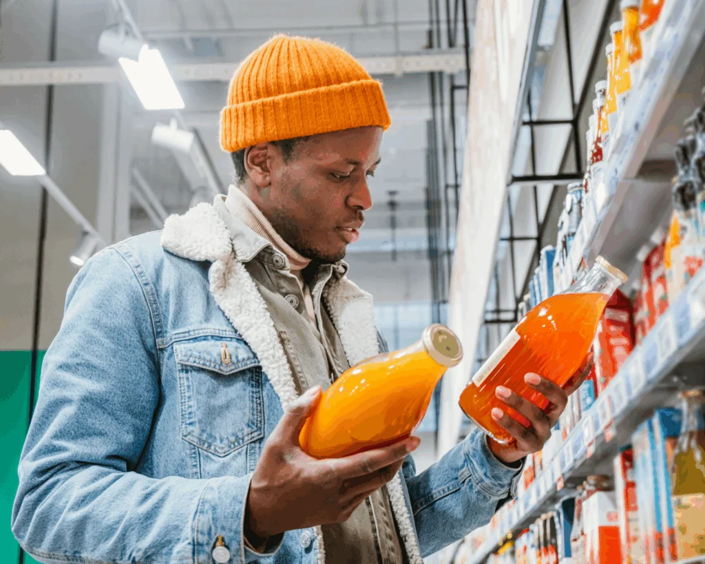 portrait of a young Black man looking at beverage products while grocery shopping
