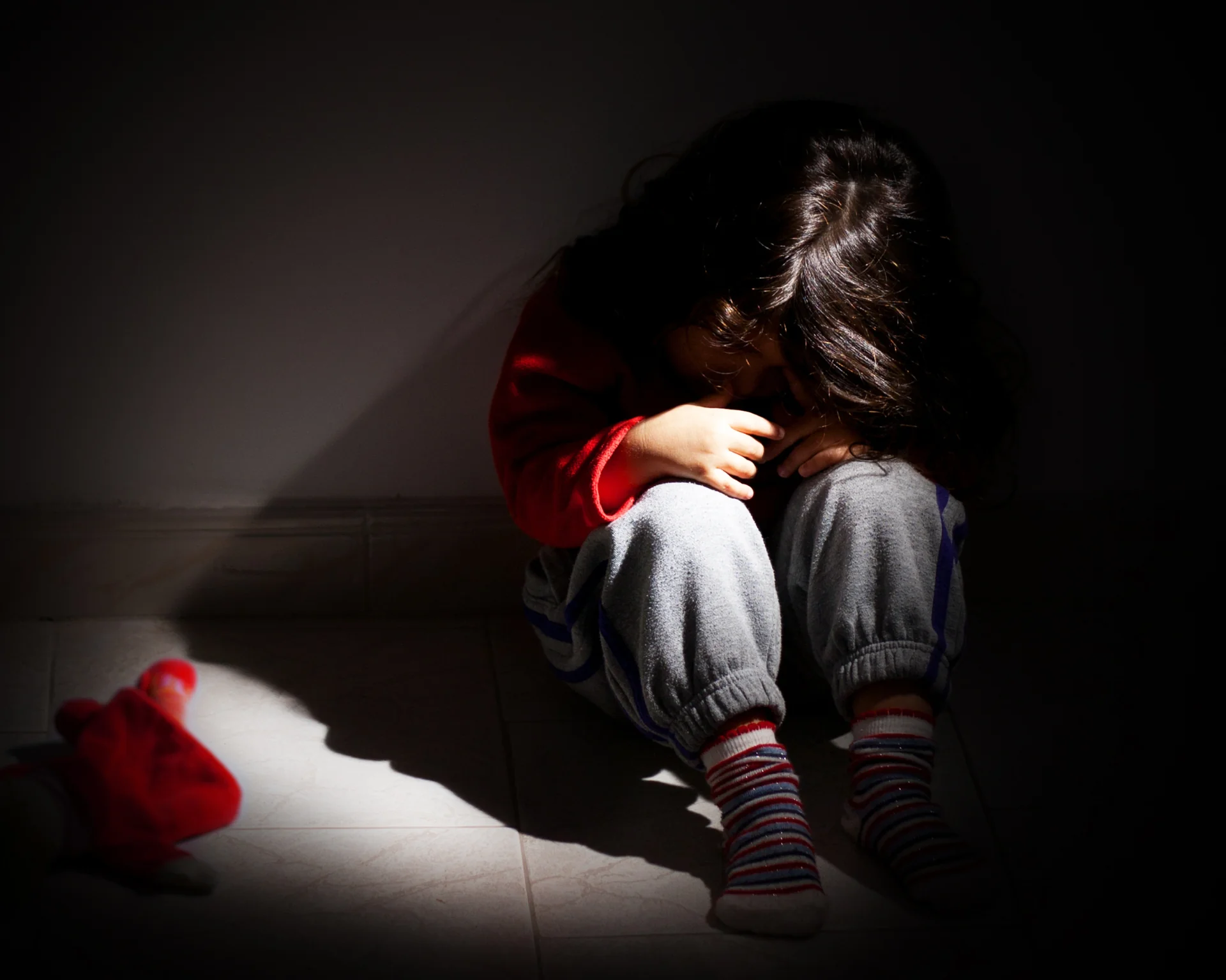 Young girl upset and sitting alone in the dark. Child abuse concept