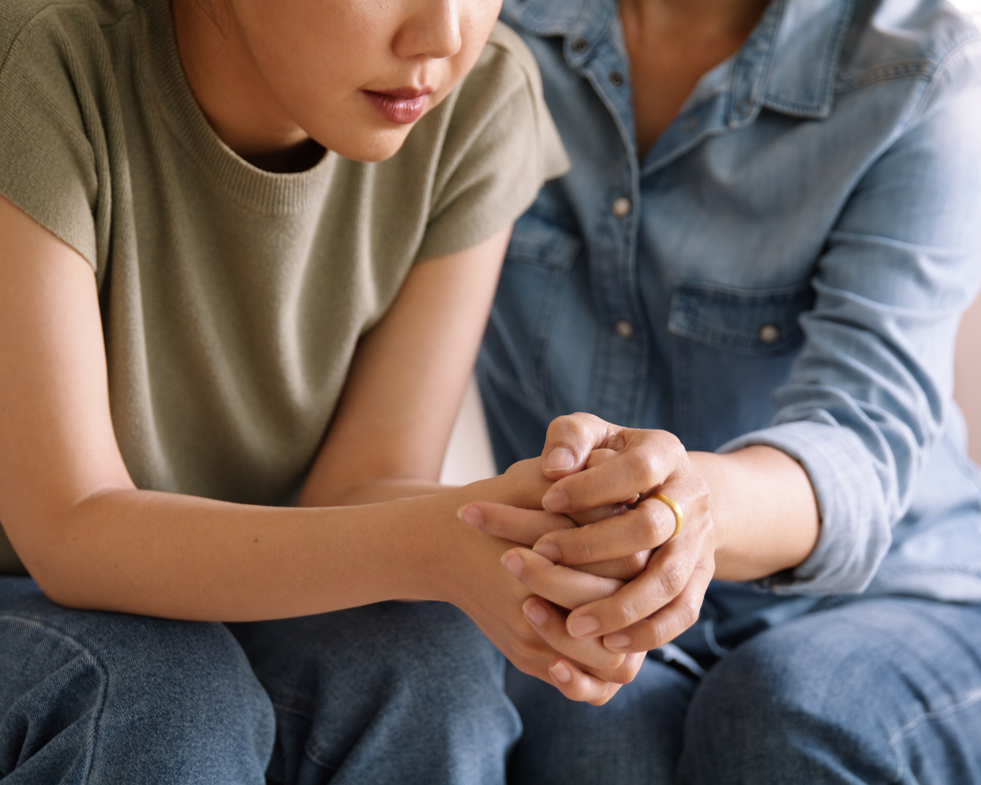 Portrait of a mom holding hands of her teen daughter to bring her trust and comfort. Mental health care and support concept