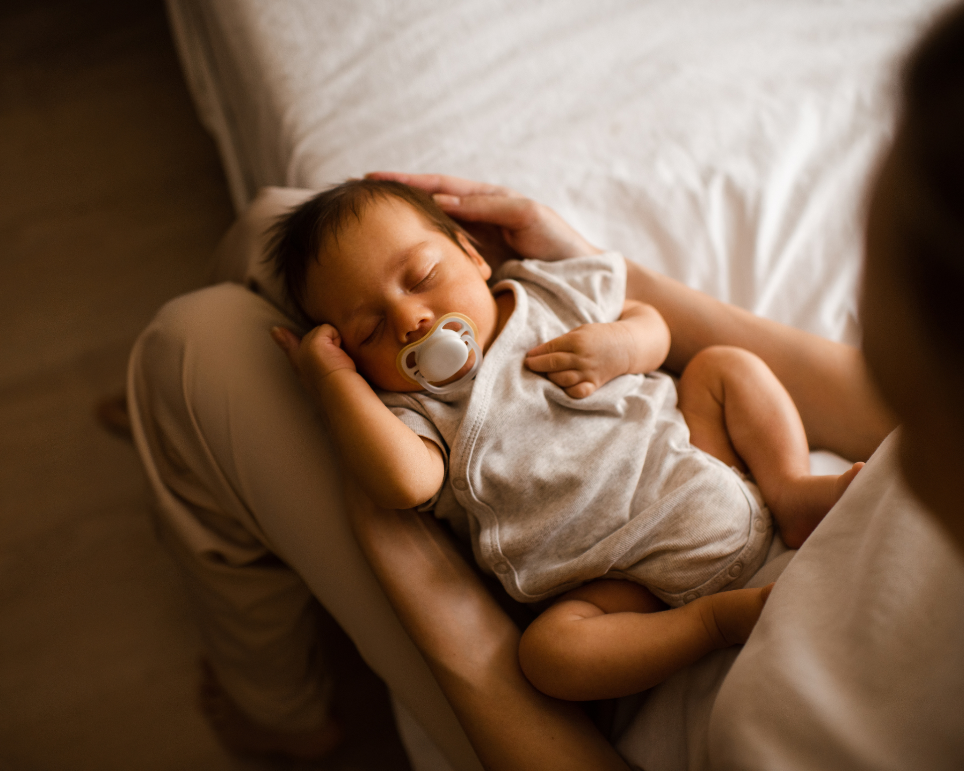 Portrait of a sleeping baby lying on its mother's lap.