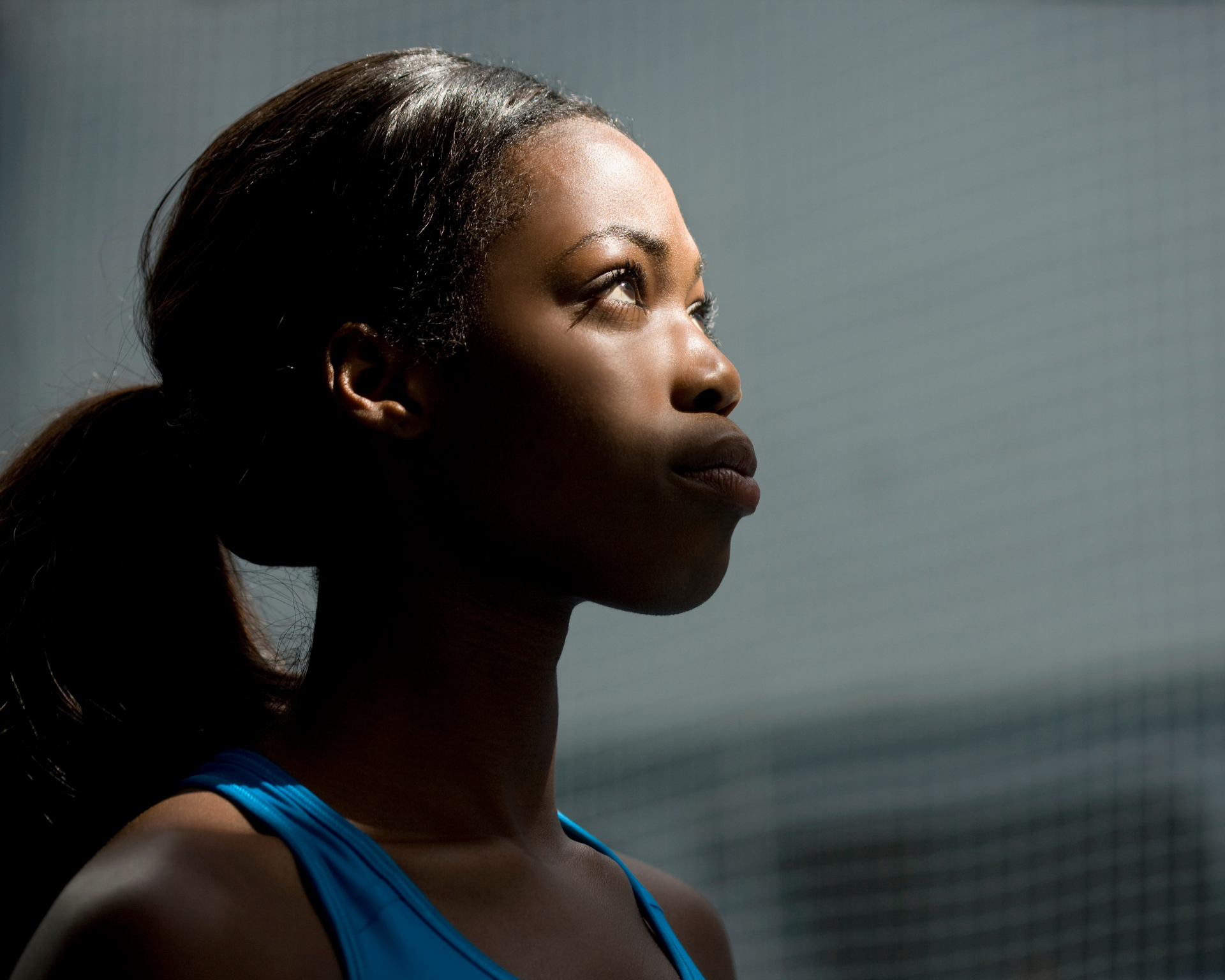 Portrait of a young woman in workout gear, looking up into the light