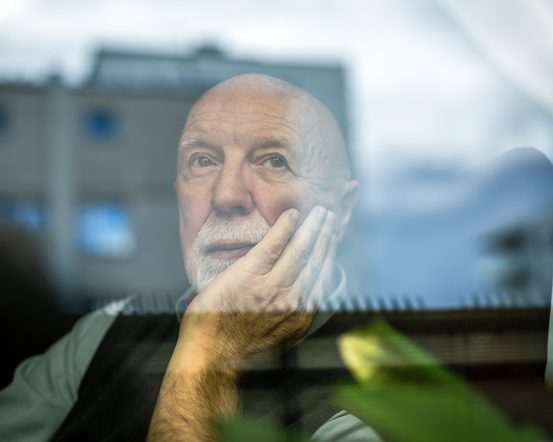 Portrait of a thoughtful older man looking through a window. Lifespan and aging concept