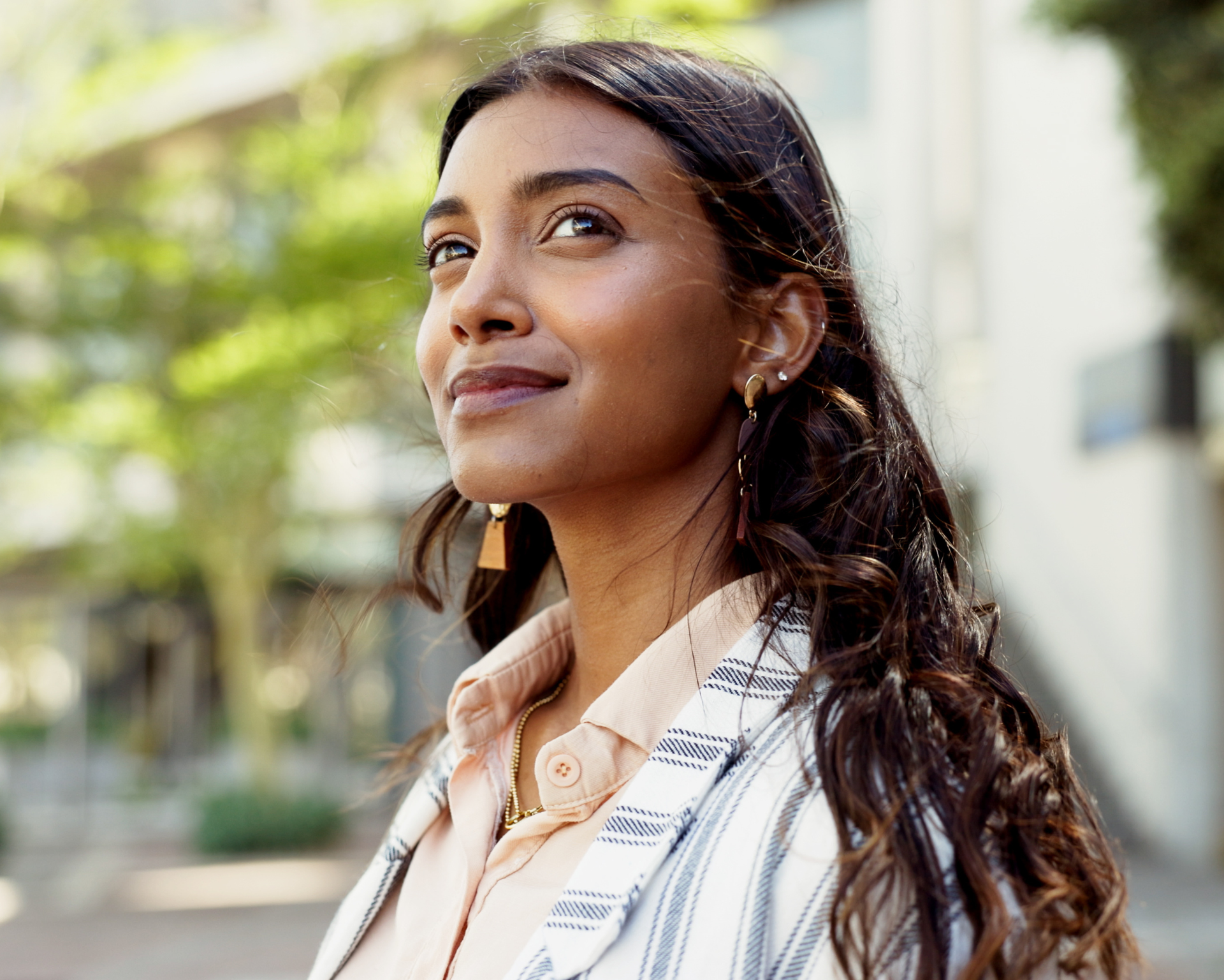 Portrait of a young woman on a city sidewalk looking off in distance. Meant to evoke motivation seeking