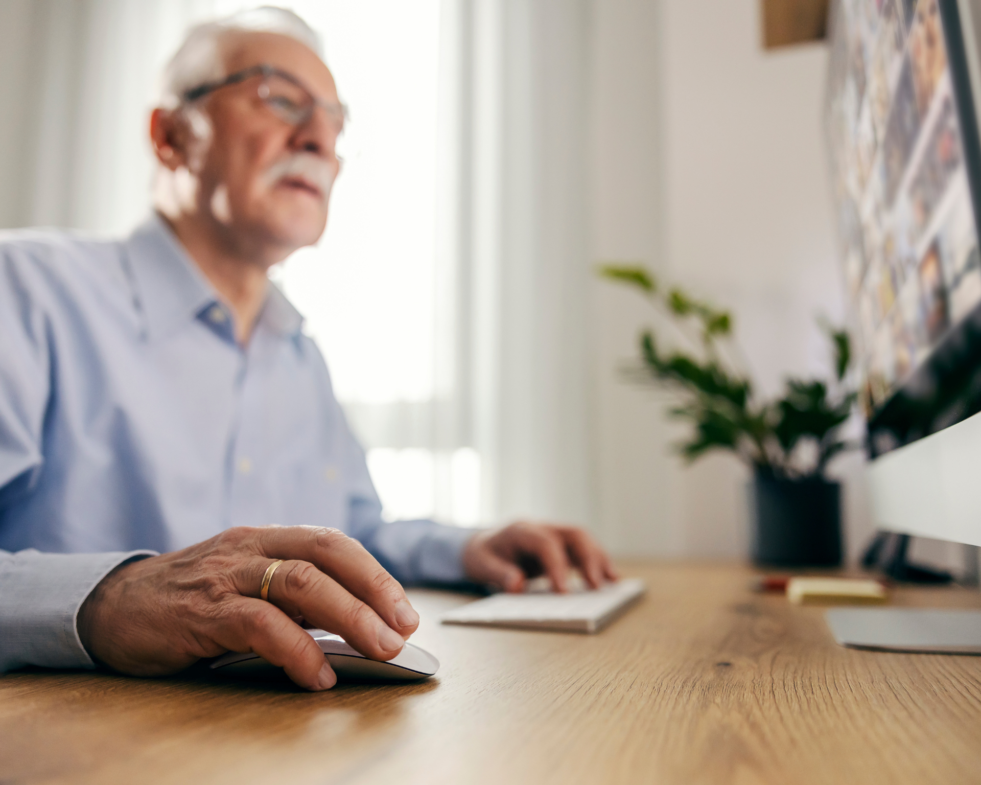 Close up of a senior man's hand using computer mouse, scrolling on internet. Misinformation exposure concept