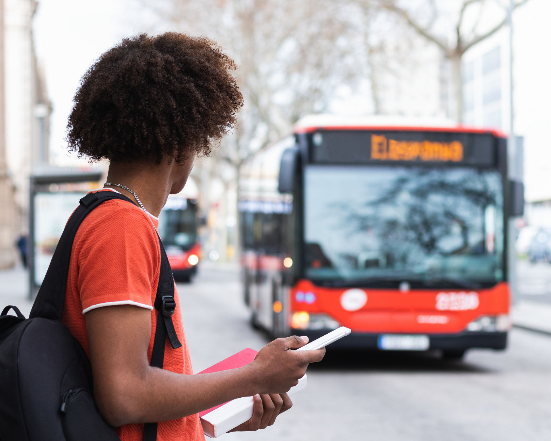 young Black man waiting at bus stop, looking at approaching bus