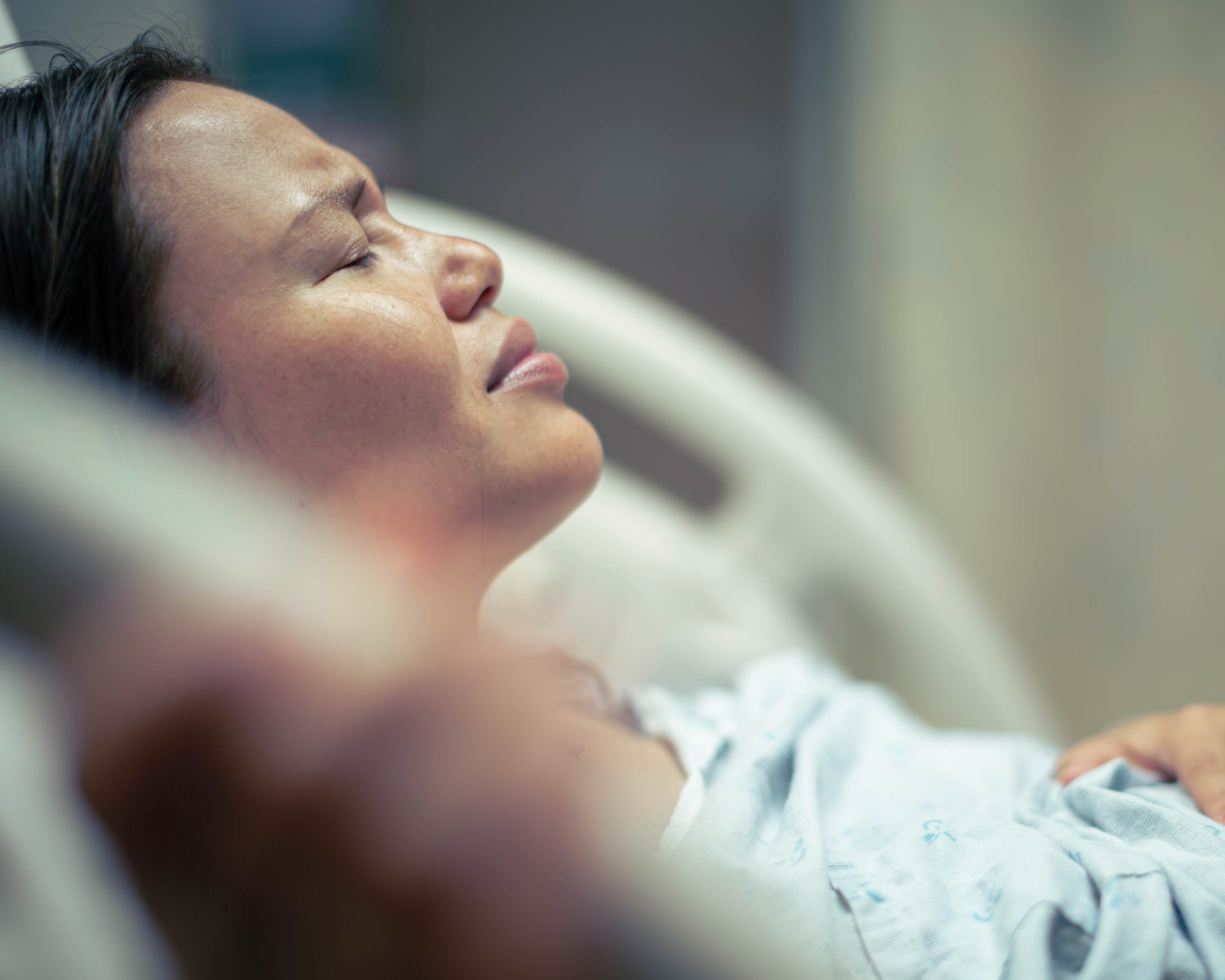 Female patient in bed at the hospital suffering from pain. Maternal health concept