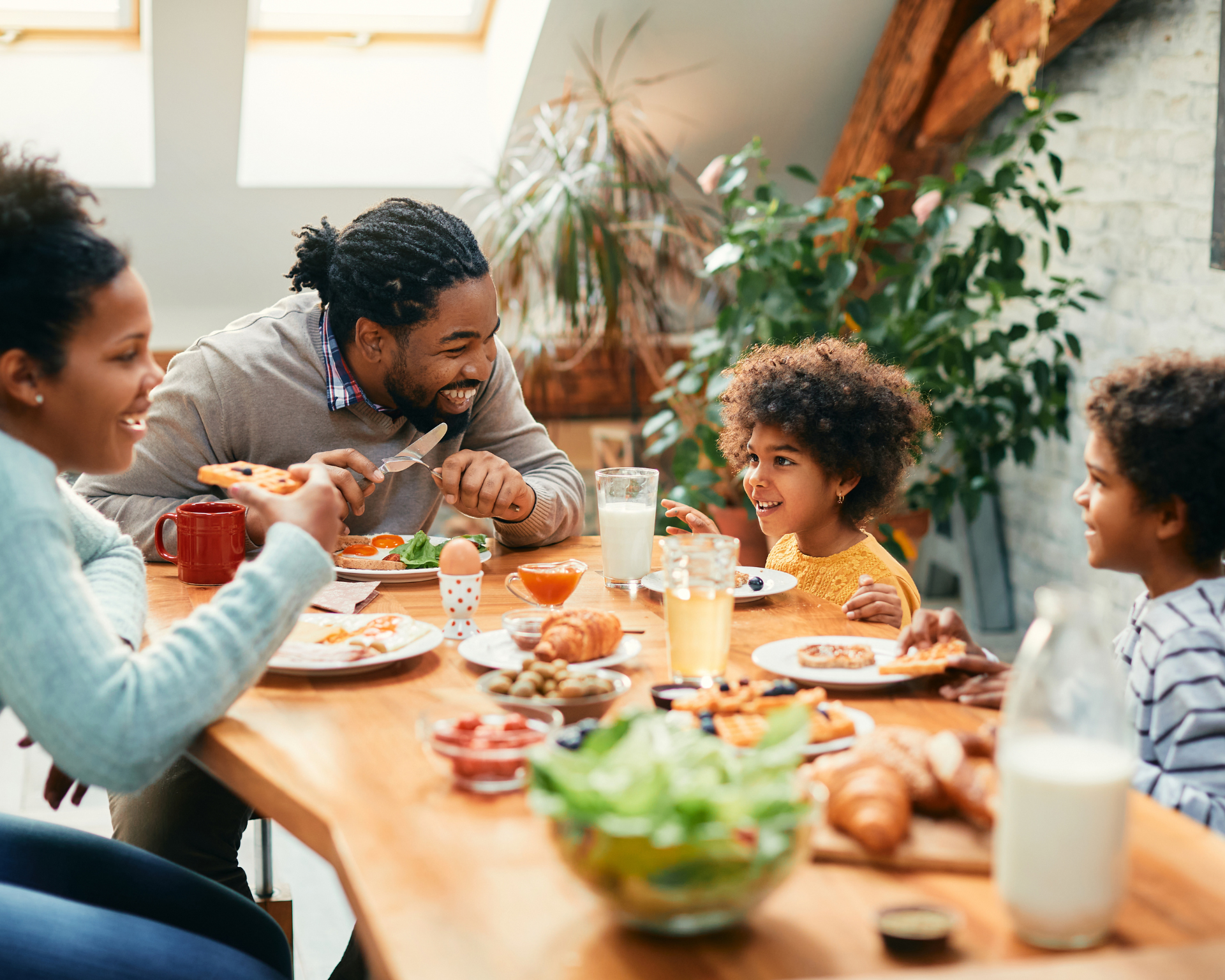Happy parents and their kids talking over a meal together in the dining room.