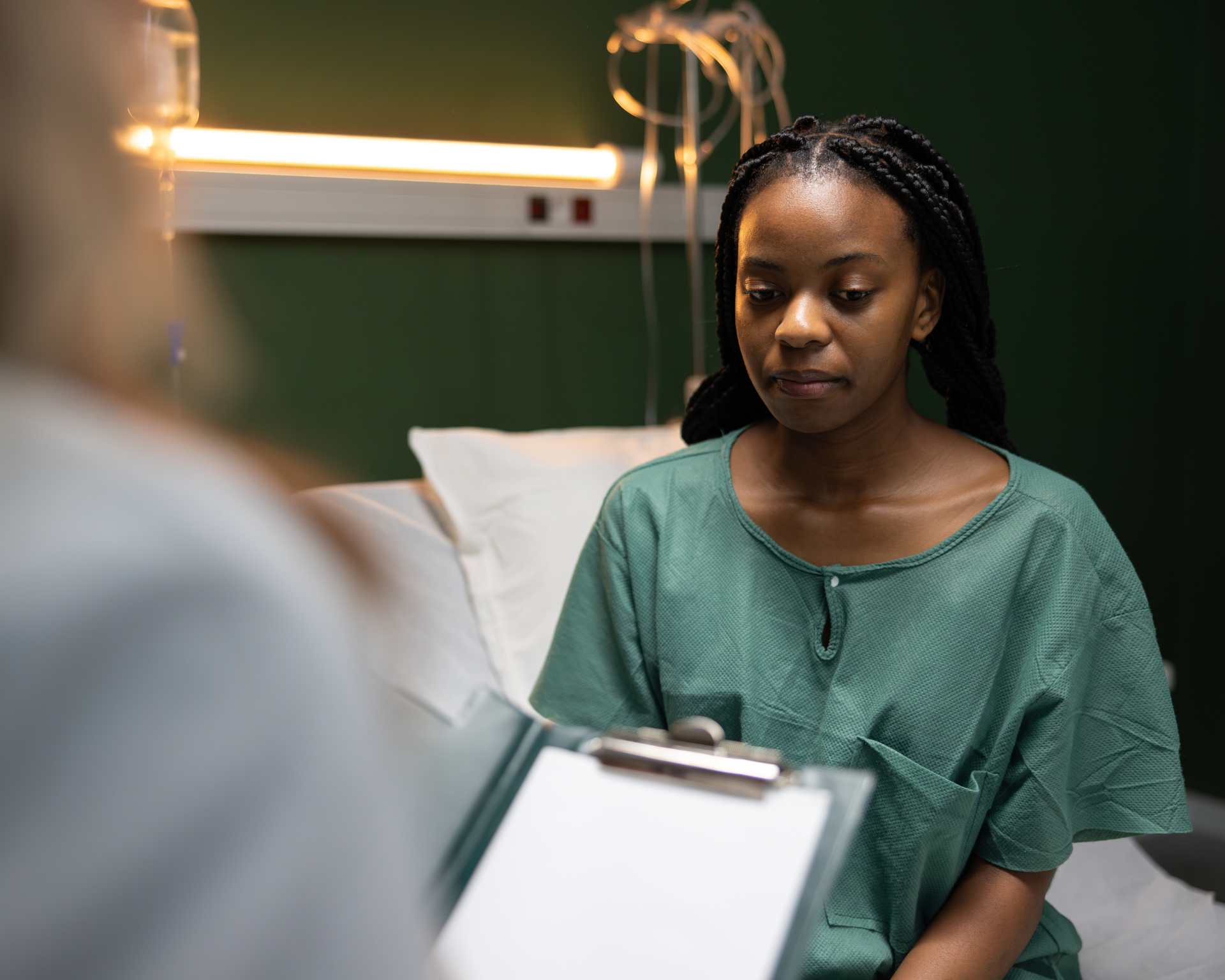 Young Black female sickle cell disease patient talks to White doctor