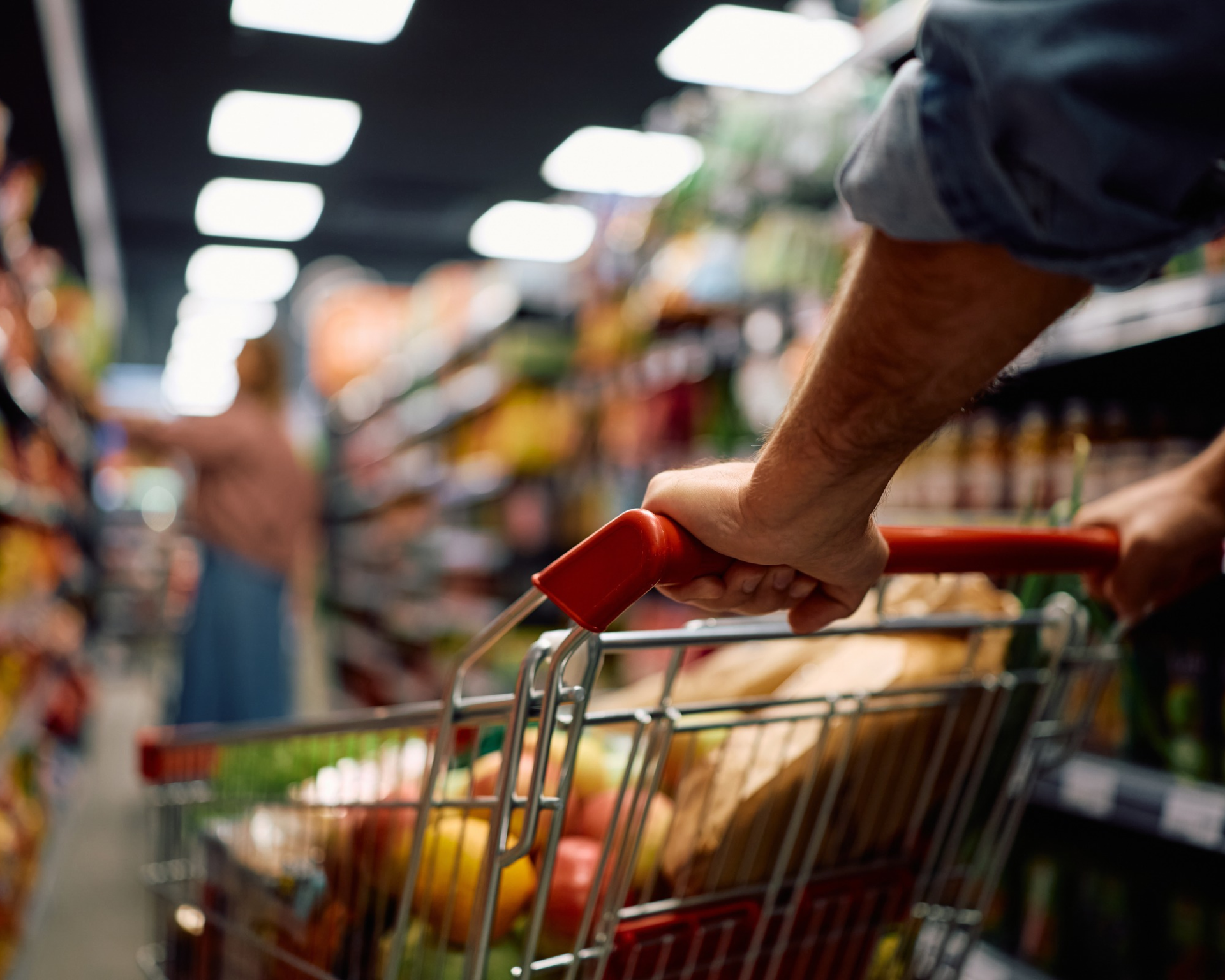 Close up of man pushing shopping cart with groceries through the store.