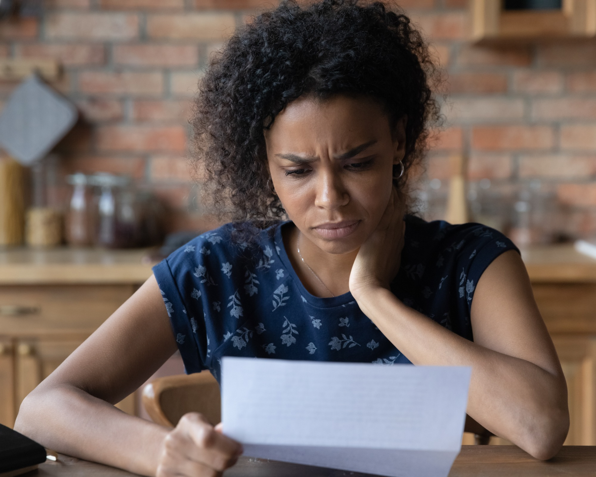 Portrait of a stressed young Black woman looking at medical bills. Loss of Medicaid coverage concept